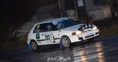 a white car driving down a wet road