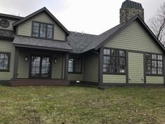 a gray house sitting on top of a lush green field