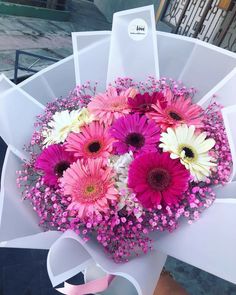 a bouquet of pink and white flowers sitting on top of a table