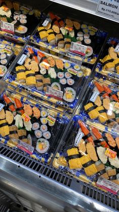 an assortment of sushi and other food items on display in a deli case