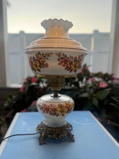 a white and gold vase sitting on top of a blue table