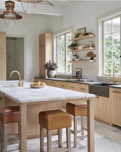 a large kitchen with an island in the middle and two stools at the end