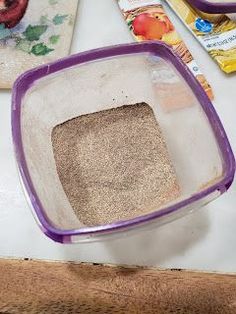 a purple and white cat litter box on a table next to some food, including an apple