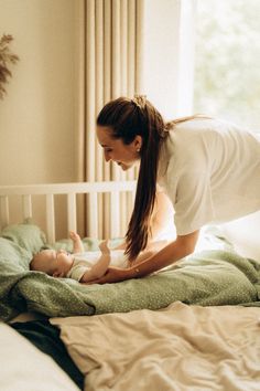 a woman is playing with her baby on the bed