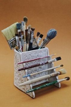 a cup filled with lots of different types of paintbrushes and brushes in it