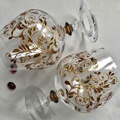 two wine glasses sitting next to each other on top of a white cloth covered table