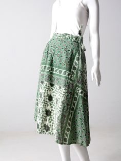 "This is a 1970s vintage wrap skirt. The all cotton skirt features a green, black and cream block floral print. It wraps closed with long ties and belt loops. A rare style with pockets at the waist! CONDITION In good condition with wear consistent with age and use. APPPROXIMATE FIT: S/M MEASUREMENTS Fits Waist Best: 26\" - 30\" .. 33 cm - 76.2 cm Waistband open: 35.5\" ... 90.2 cm Ties each: 27\" ... 68.6 cm Length: 29\" ... 73.7 cm HOW WE MEASURE * Skirt measured lying flat * Waistband open mea Green Bohemian Wrap Skirt For Spring, Bohemian Green Long Wrap Skirt, Green Bohemian Long Wrap Skirt, Green Cotton Wrap Skirt For Spring, Spring Green Cotton Wrap Skirt, Retro Green Long Skirt, Retro Green Long Skirt Bottoms, Green Block Print, Vintage Wrap Skirt