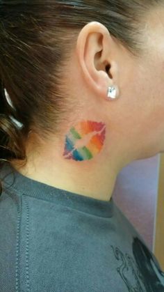 a woman's neck is adorned with multicolored lipstick kisses on her left side