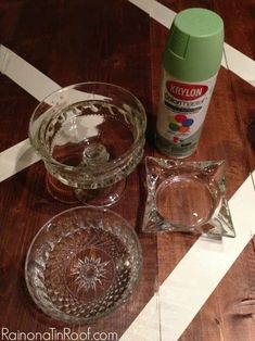 some glass dishes are sitting on a wooden table next to a bottle of glue and scissors