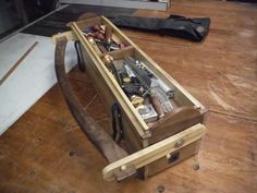 a wooden box filled with tools on top of a hard wood floor