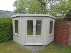 a small white shed sitting in the middle of a yard