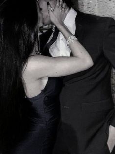 a man in a suit and tie kissing a woman