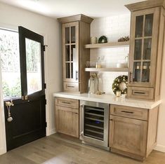 a kitchen with wooden cabinets and white counter tops next to a black door that leads to a patio