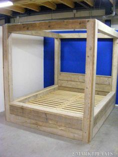 a bed frame made out of pallets in a room with blue walls and concrete flooring