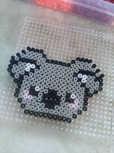 a beaded sheep is sitting on the floor next to a plastic container filled with beads