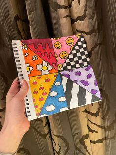 a person holding a notebook with four different designs on it