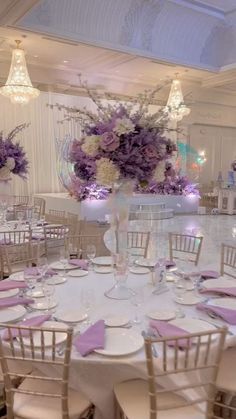 the tables are set up with purple and white centerpieces for an elegant wedding reception