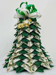 a green and white christmas tree made out of folded paper with a gold ornament on top