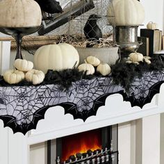 a fireplace decorated for halloween with white pumpkins, candles and black lace on the mantle