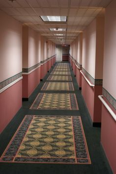 a long hallway with carpeted floors and pink walls