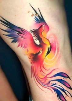 a colorful bird tattoo on the back of a woman's leg with watercolors