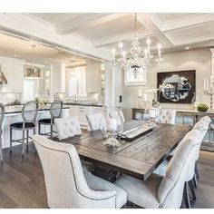 the dining room table is surrounded by white chairs and chandeliers in this elegant kitchen