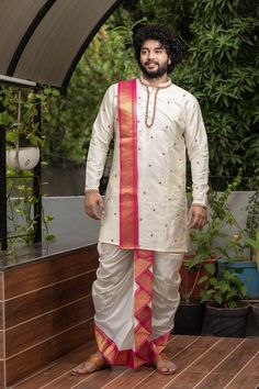 a man standing on a deck wearing a white outfit with red and gold trims