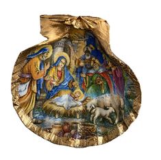 the nativity scene is painted on an ornate gold platter with a golden ribbon around it