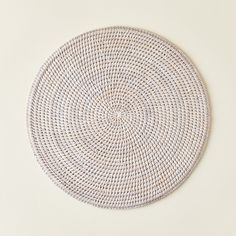 a round woven placemat on a white surface with no one in the room around it