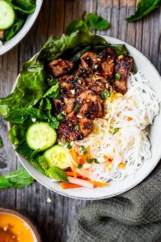 a white bowl filled with meat and veggies on top of a wooden table