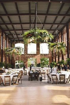 an indoor venue with tables and chairs covered in greenery