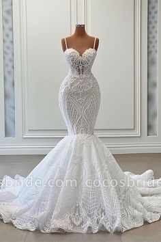 a white wedding dress on a mannequin in front of a wall with doors