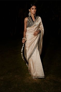 Editor's Note Featuring a beige stripe sari with tarnished silver vintage zardozi embroidery in Aztec and flora inspired artworks on the border. It comes with black sleeveless blouse with a greek-roman influence and Victorian elements. Fabric: Silk and tissue Color: Beige, black Sleeves: Sleeveless Neckline: V-neck Component: Sari and blouse Occasion: Wedding Guest Disclaimer: Product colour may slightly vary due to photographic lighting sources Care: Dry Clean Only About the Designer Matsya by Classy Saree Look, Victorian Elements, Traditional Blouses, Embroidery Zardozi, Zardozi Embroidery, Royalty Aesthetic, Black Sleeves, Black Sleeveless Blouse, Beige Outfit