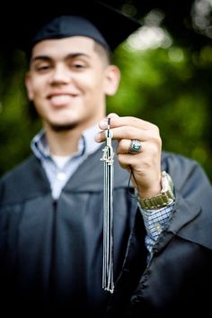 a man in graduation cap and gown holding up a tassel with a ring on it