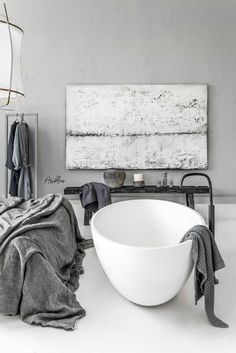 a large white bowl sitting on top of a bathroom floor next to a towel rack