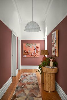 a hallway with pink walls and wooden flooring next to a painting on the wall