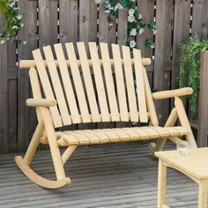 a wooden rocking chair sitting on top of a wooden deck next to a small table