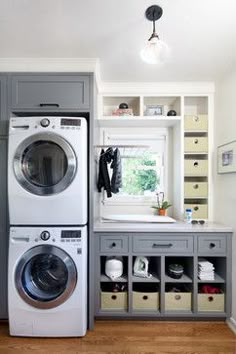 a washer and dryer in a small room with built - in shelving