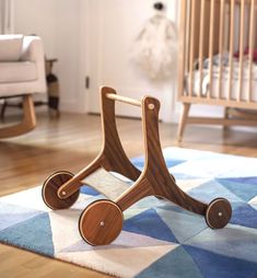 a wooden toy car sitting on top of a blue and white rug in front of a crib