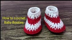 red and white crocheted baby booties sitting on top of a wooden table