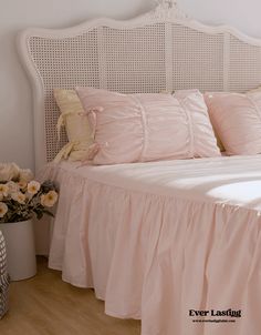 a white headboard with pink sheets and pillows on top of it in a bedroom