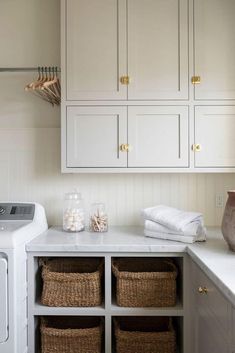 a washer and dryer in a white laundry room with baskets on the counter