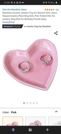 a pink heart shaped dish with two wedding rings on it