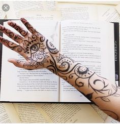 a person's arm and hand with tattoos on it next to an open book