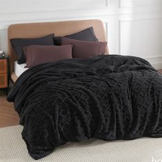 a bed covered in black blankets and pillows