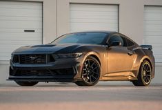 a silver mustang parked in front of two garage doors