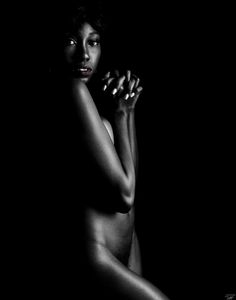 a naked woman posing in the dark with her hands on her hips and one hand behind her head