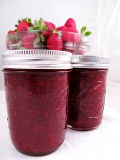 two mason jars filled with raspberry jam and fresh strawberries