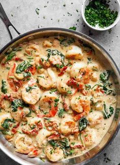 a pan filled with shrimp and spinach covered in white sauce on top of a table