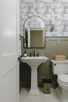 a white toilet sitting next to a sink in a bathroom under a mirror above it